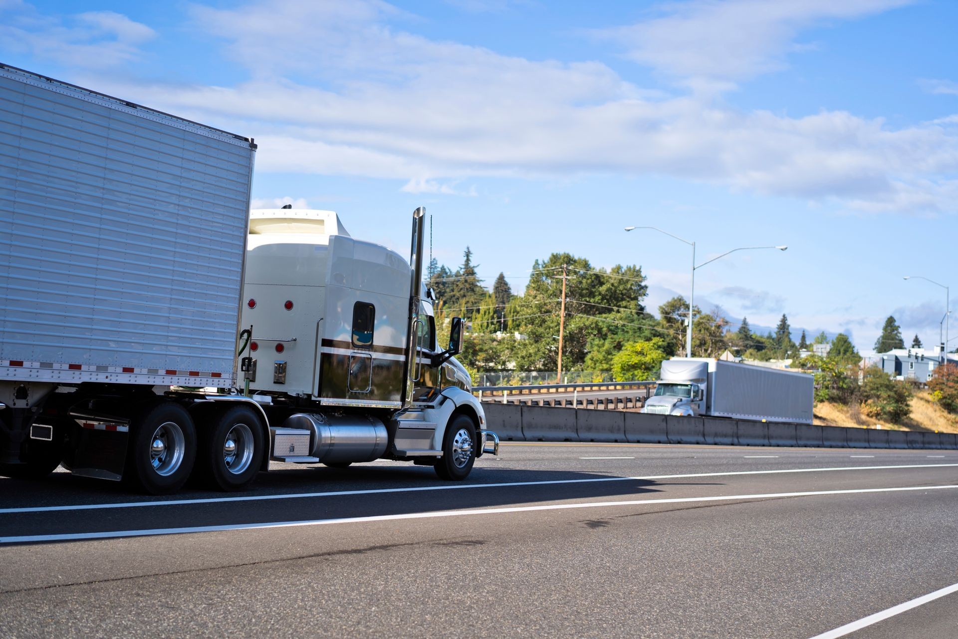 Professional commercial big rigs white semi trucks transporting refrigerated semi trailers running towards each other in the opposite direction on the wide highway in sunny day